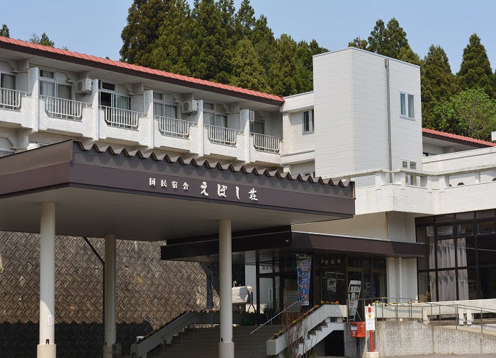 外壁が白で屋根がオレンジの国民宿舎えぼし荘の入口からの外観を写した写真