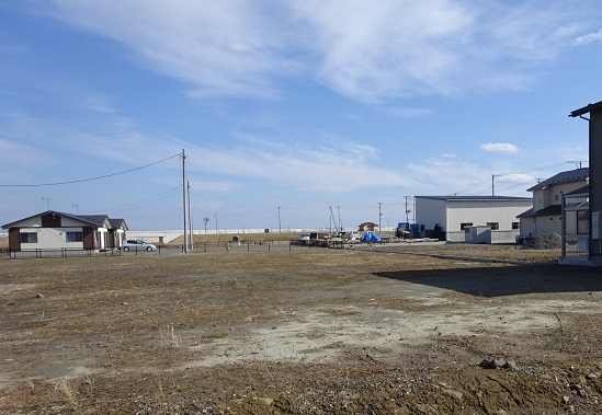 周辺に3軒ほどの建物がある広々とした旭町地区の空き地の写真