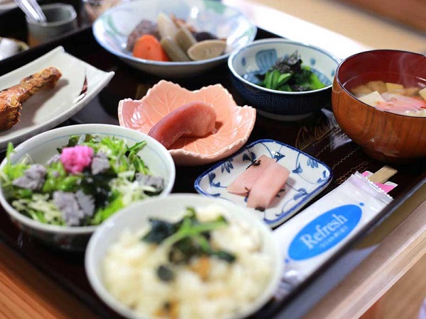 お盆の上に並べられた炊き込みご飯や汁物、お漬物、焼き魚、煮物などのおまかせ御膳の写真