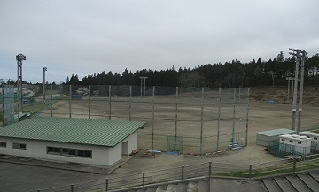 バックネットとや夜間照明設備が設置されている広々とした山村広場の写真