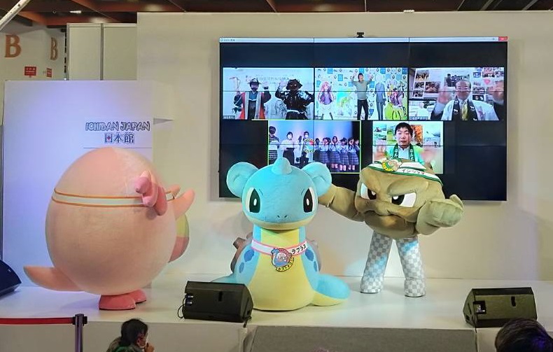 後ろに大きな液晶画面が設置されているステージ上に立っている3体のゆるキャラをアップで撮影した写真