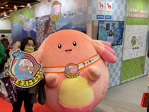 女性がピンク色のゆるキャラと一緒に撮影している写真