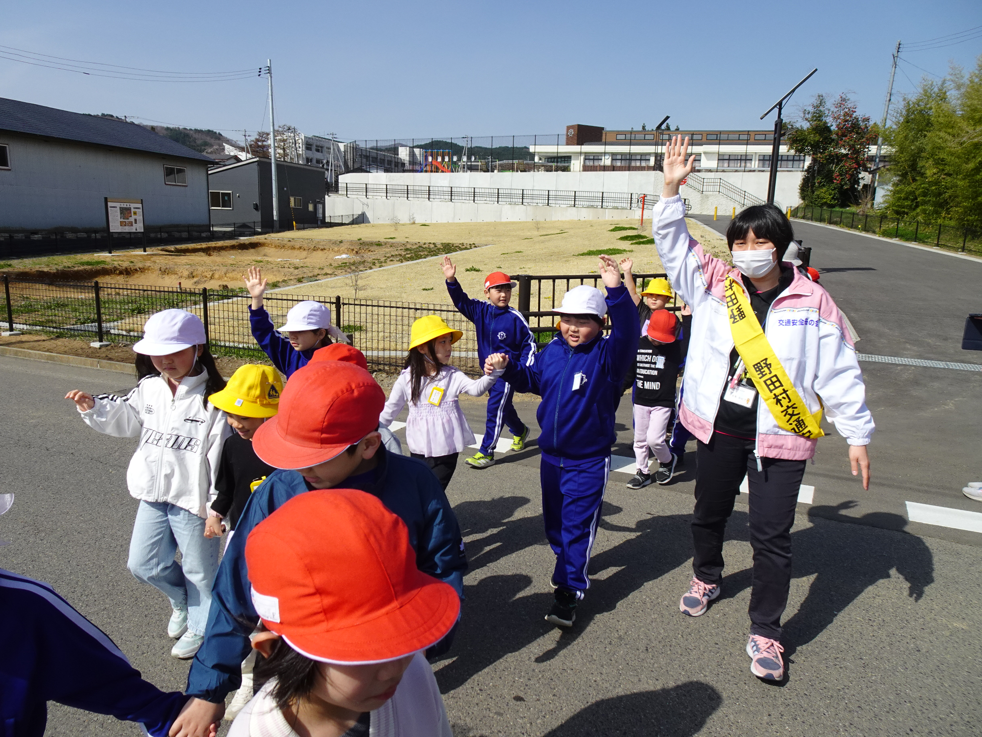手を挙げて道路を横断する児童たち
