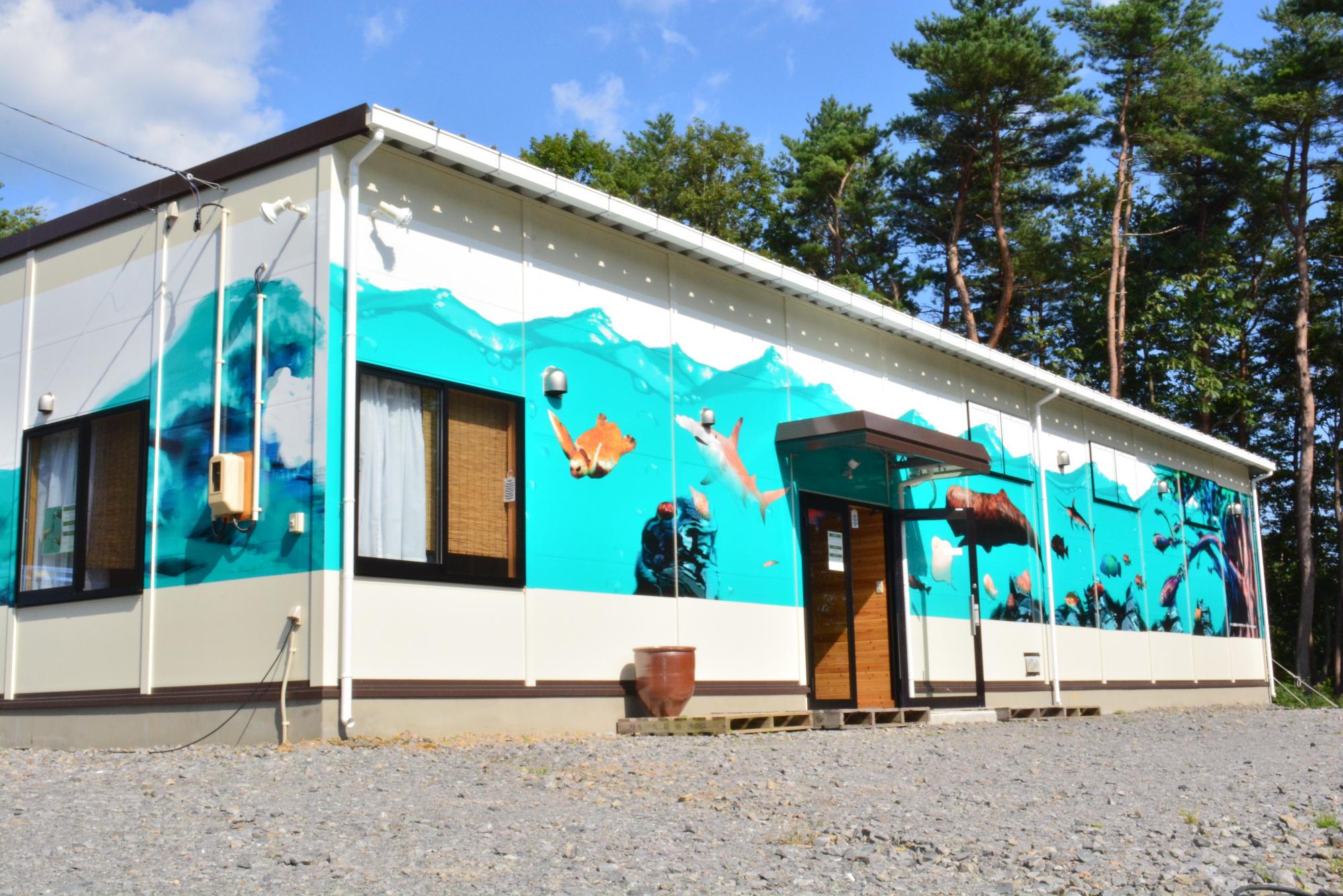 建物の壁にウミガメやサメなどの海の生き物が描かれている美術館の建物の写真