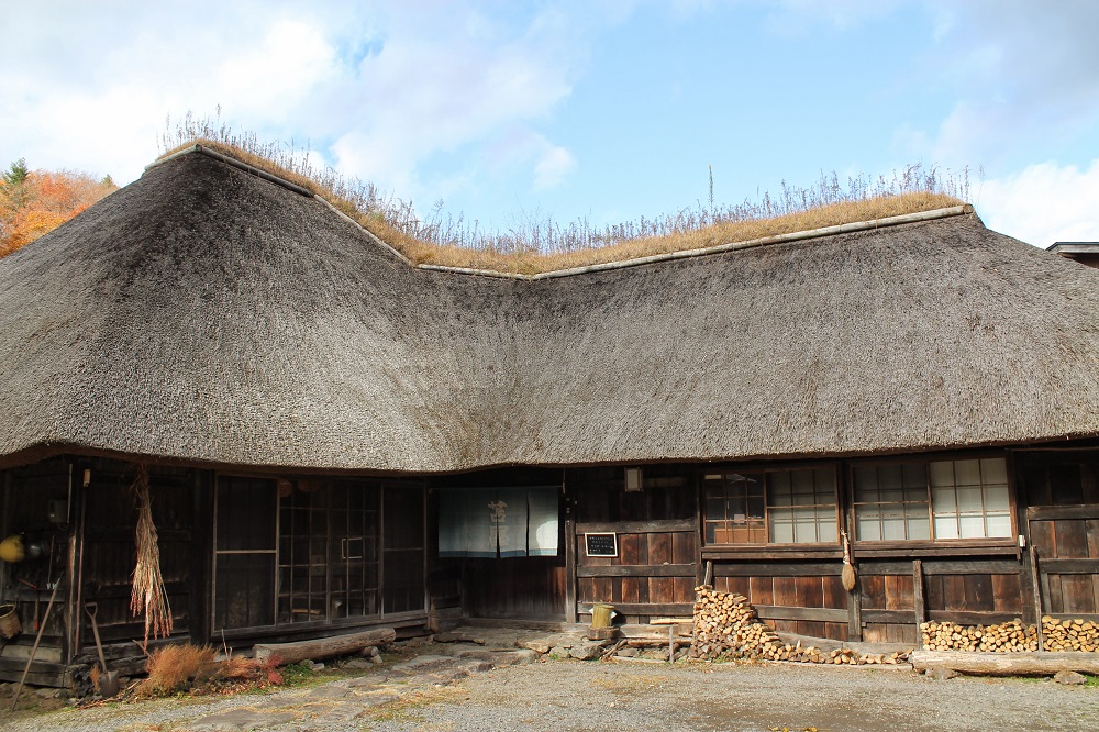 かやぶき屋根でL字型の平屋づくり、入り口に「苫屋」と書かれた暖簾がかけてある建物の外観写真