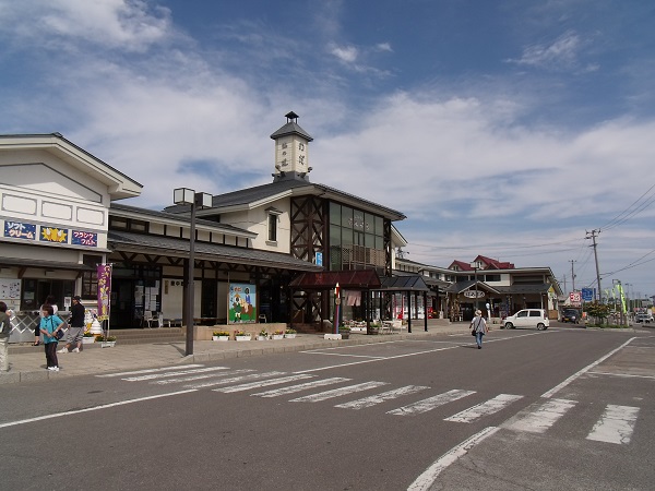 道路沿いにソフトクリームやフランクフルトのお店や観光物産館の建物が並んでいる観光物産館 ぱあぷるの外観写真