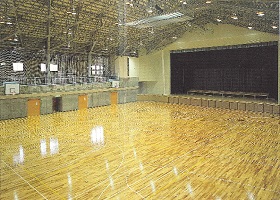 前方にステージがあり、観客席が2階に設置されている広々とした体育館の室内写真