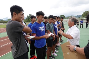 野田村の特産品を渡されている台湾陸上チームの選手の写真