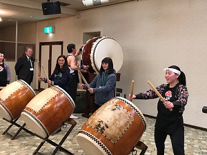 なもみ太鼓のメンバーに和太鼓の演奏の仕方を教わっている台湾陸上関係者の写真