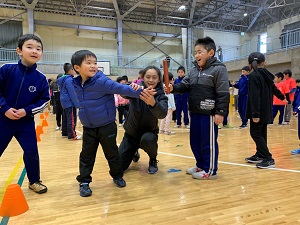 体育館で子供の腕を持って走り方のフォームを教えている台湾陸上選手の写真