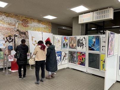 聖火リレートーチやアートポスターの展示を見ている人達の写真