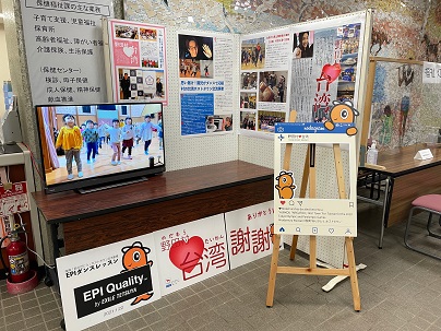 長机の上に設置されたテレビに映像が流れ、囲むように設置された掲示板にポスターが貼られている台湾ブース展示の写真
