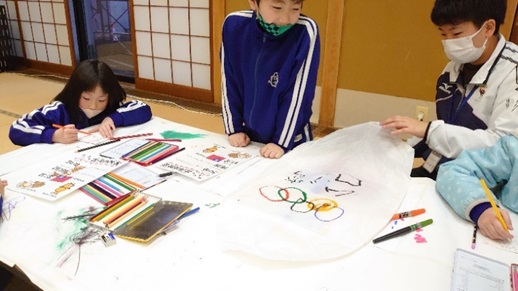 青色のジャンパーを着た子供たちが、それぞれペンなどを使いランタンを制作している様子の写真