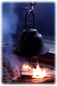 火の入った囲炉裏に吊るされた鉄瓶の写真