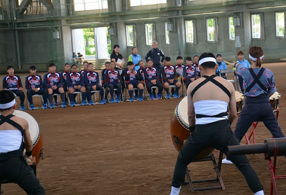 グラウンドでなもみ太鼓の演奏に聞き入る台湾ソフトボールチームの写真