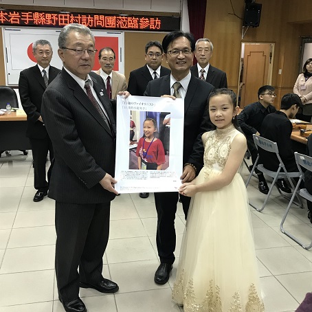 野田村長、彰化市の代表者、白いドレスを着た張さんが3人で一緒に一枚のポスターを持って立っている写真